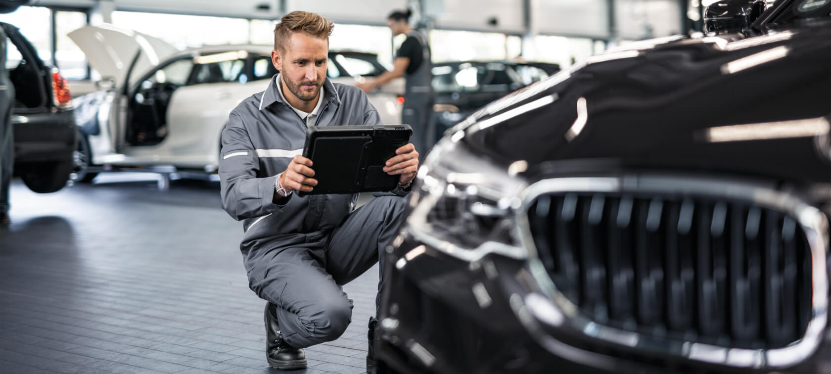 BMW herstelwerkzaamheden We zien een monteur die een BMW repareert